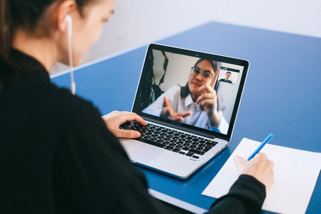 A laptop showing a grid of faces on a video conference call — the new default for remote product teams